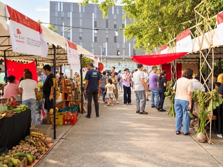 A busy Earth Market morning: shoppers between stalls of fresh produce