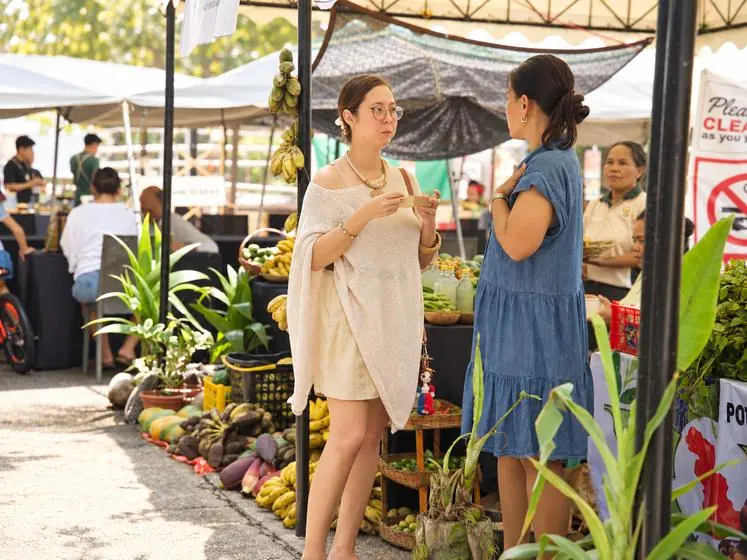 Two women chatting between market stalls of fresh produce