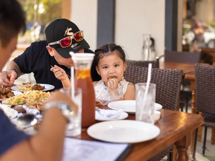 A father and his little girl at lunch, she is mid-bite